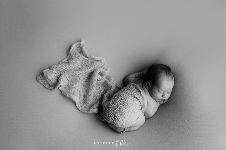 photo artistique d'un bébé allongé sur le ventre avec un lainage